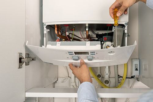 Heating technician repairing a residential boiler in Burlingame
