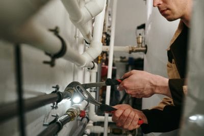 Technician inspecting commercial plumbing pipes in Burlingame